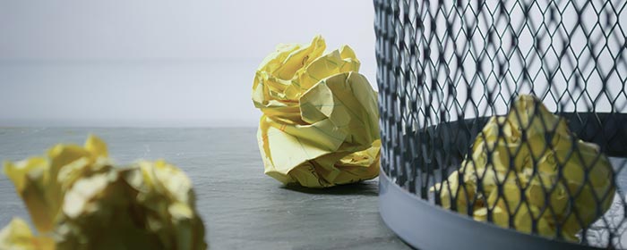 Papierkorb mit gelben zerknüllten Notiztellten